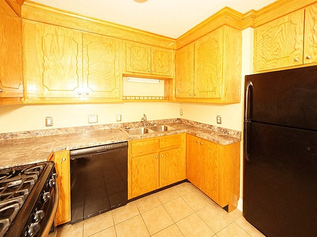 a kitchen with wooden cabinets and a black refrigerator