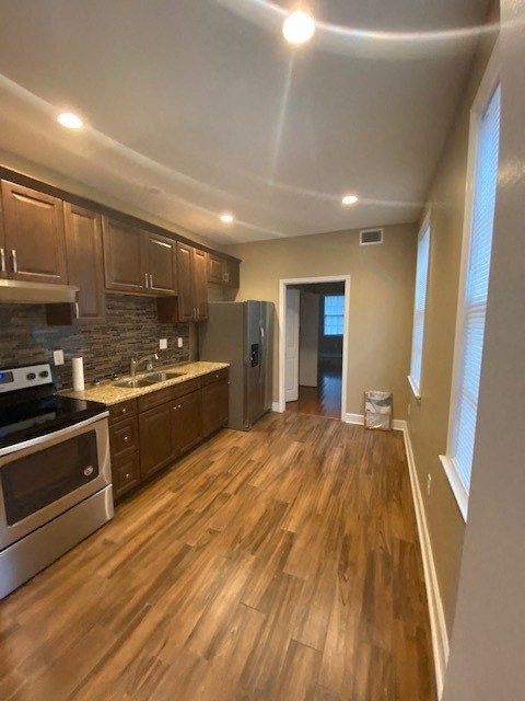 a kitchen with wooden floors and stainless steel appliances