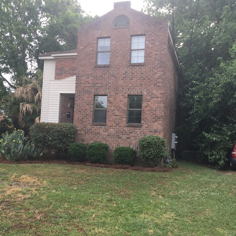 A red brick house with a white door and windows.