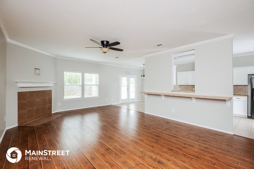 the living room and dining room with wood flooring and a ceiling fan
