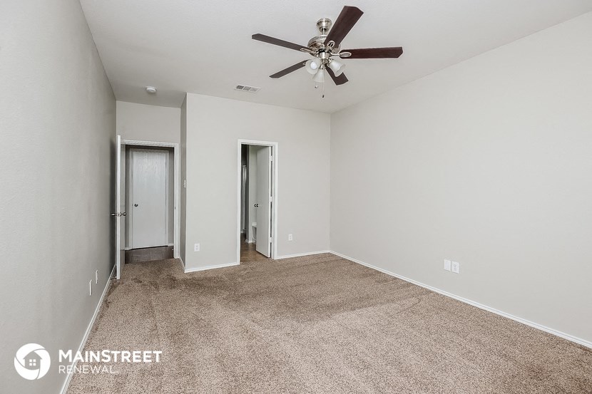 a spacious living room with carpet and a ceiling fan