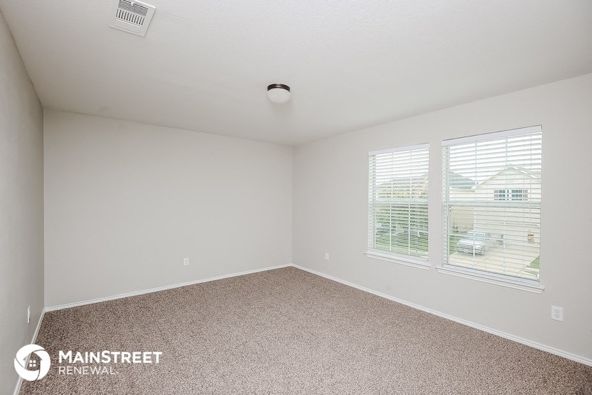 the spacious living room with two windows and carpeting