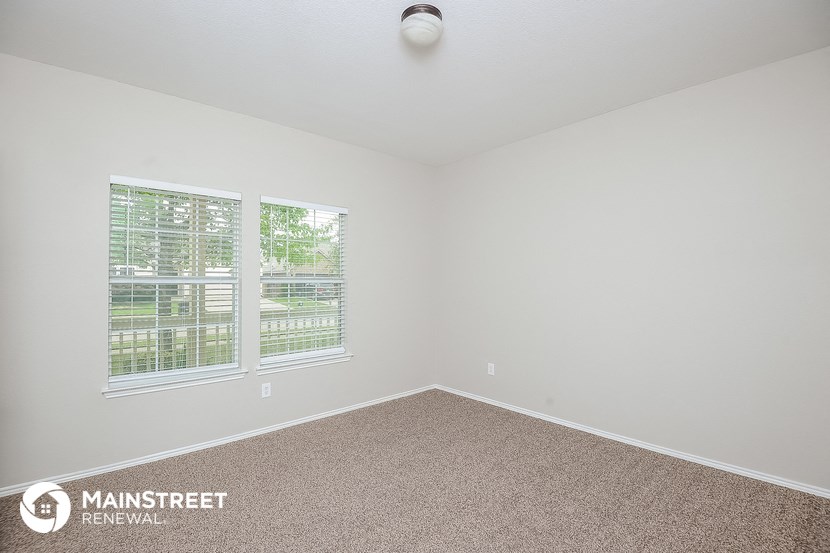 the spacious living room with two windows and carpeting