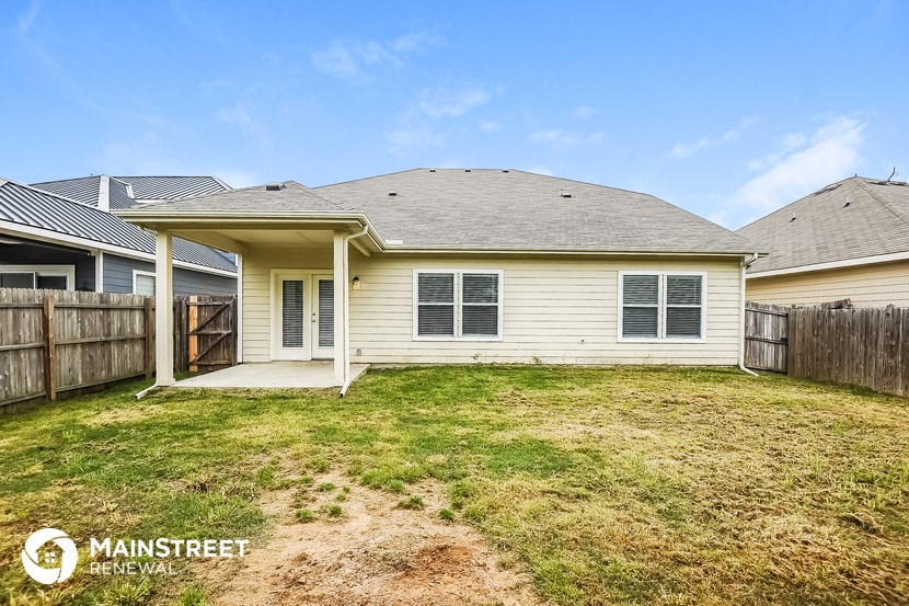 the backyard of a white house with a yard and a fence