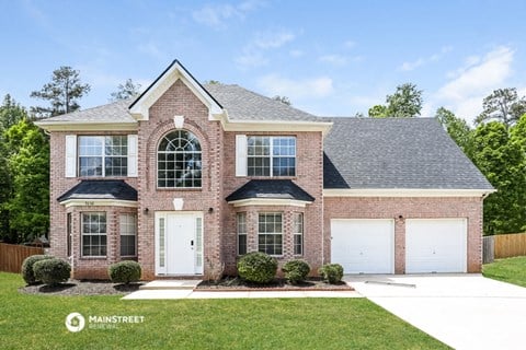 a brick house with two garage doors and a lawn