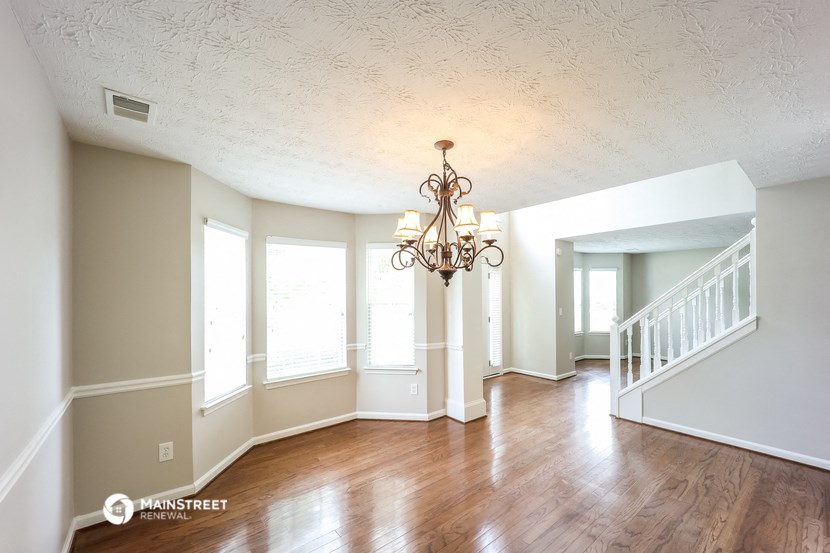 the living room and dining room of an empty house with a chandelier