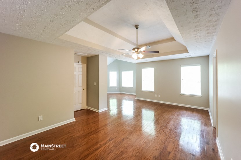 an empty living room with wood floors and a ceiling fan