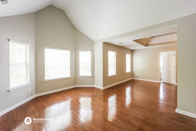 an empty living room with wood floors and windows