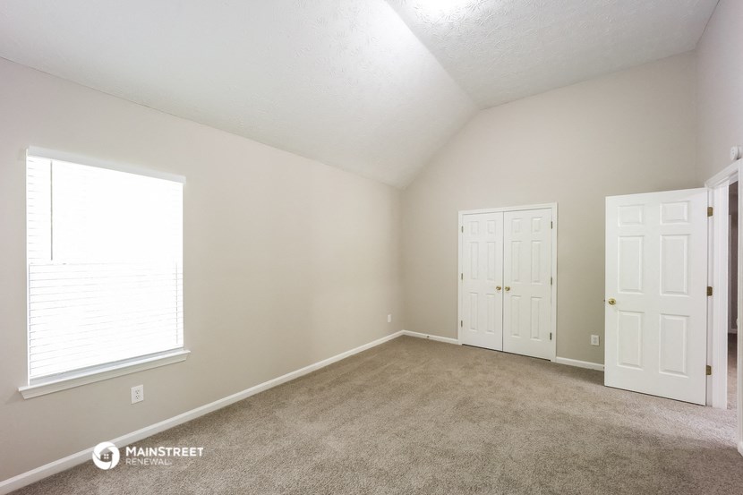 the living room of a house with a carpeted floor and two doors