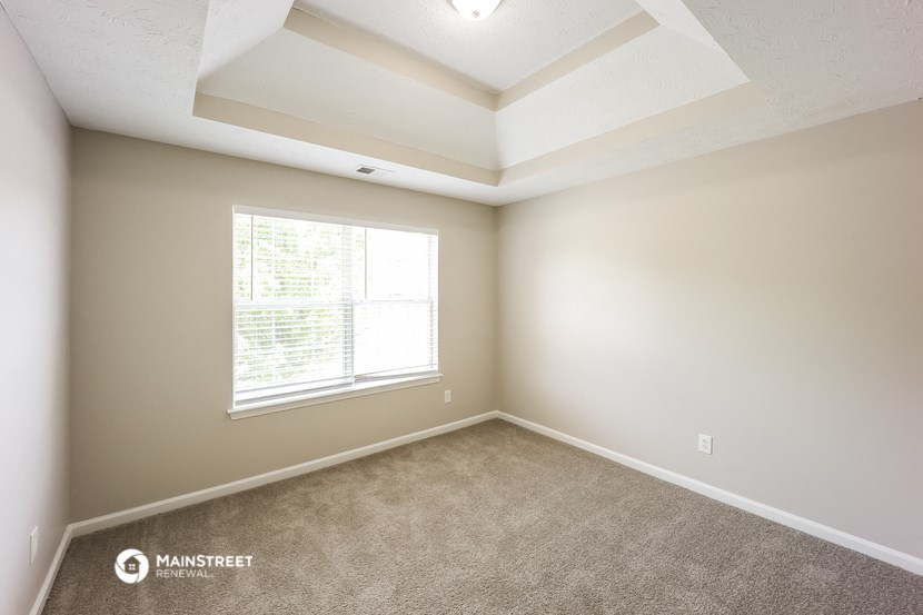 an empty room with a large window and carpet