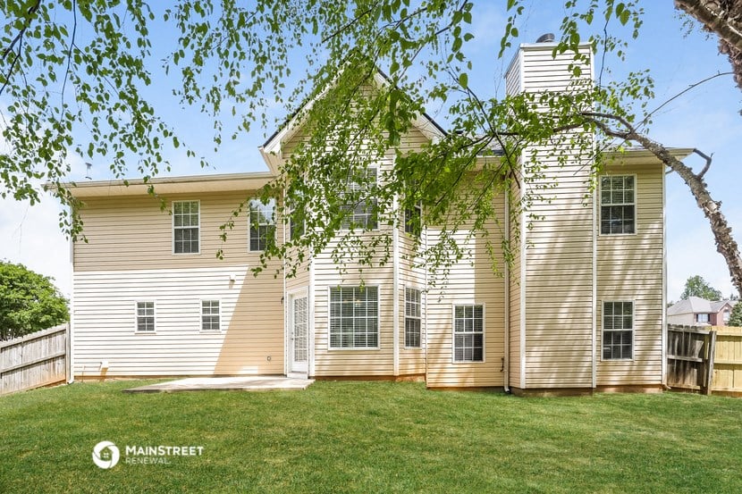 a large white house with a yard and a tree