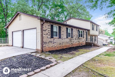 a brick house with a white garage and a sidewalk