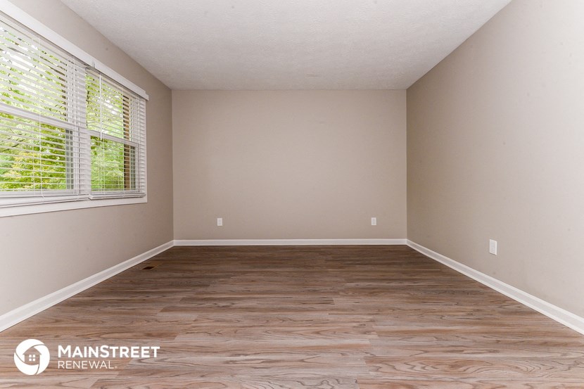 the interior of an empty room with wood flooring and a window