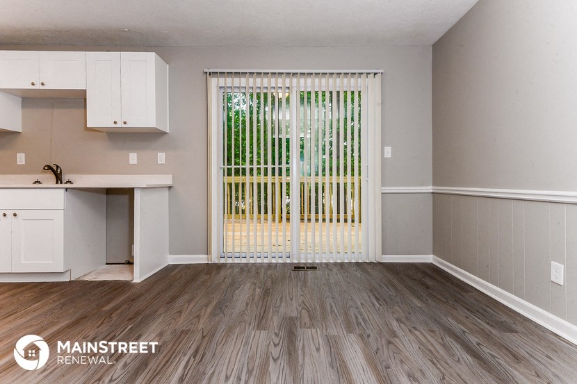 an empty living room with a door to a kitchen