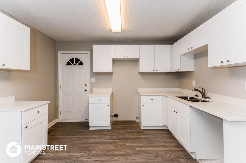 an empty kitchen with white cabinets and a sink