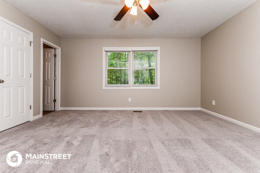 the living room of a new home with carpet and a ceiling fan