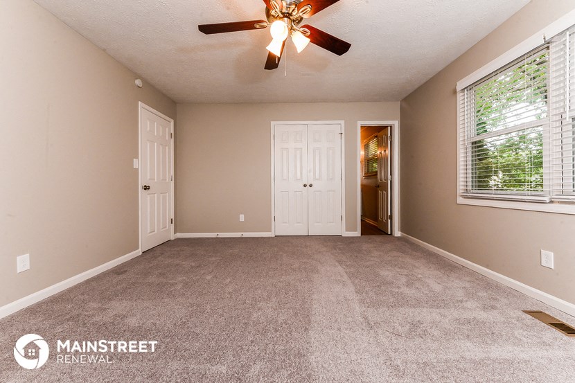 a living room with carpet and a ceiling fan