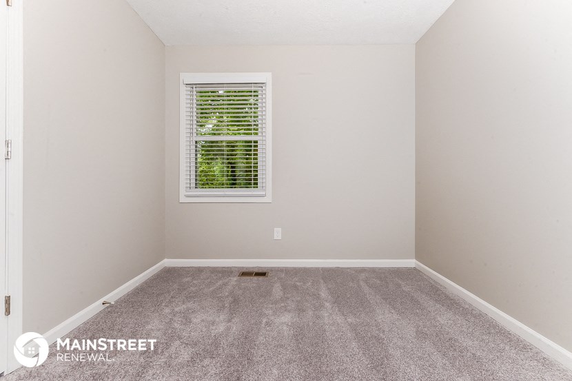 the bedroom of a rental house with carpet and a window