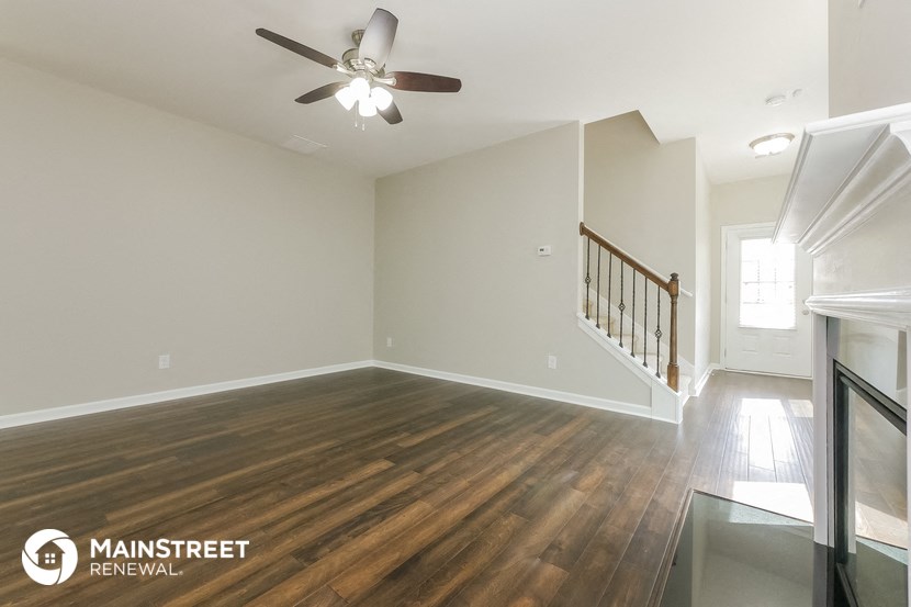 the living room with hardwood flooring and a ceiling fan