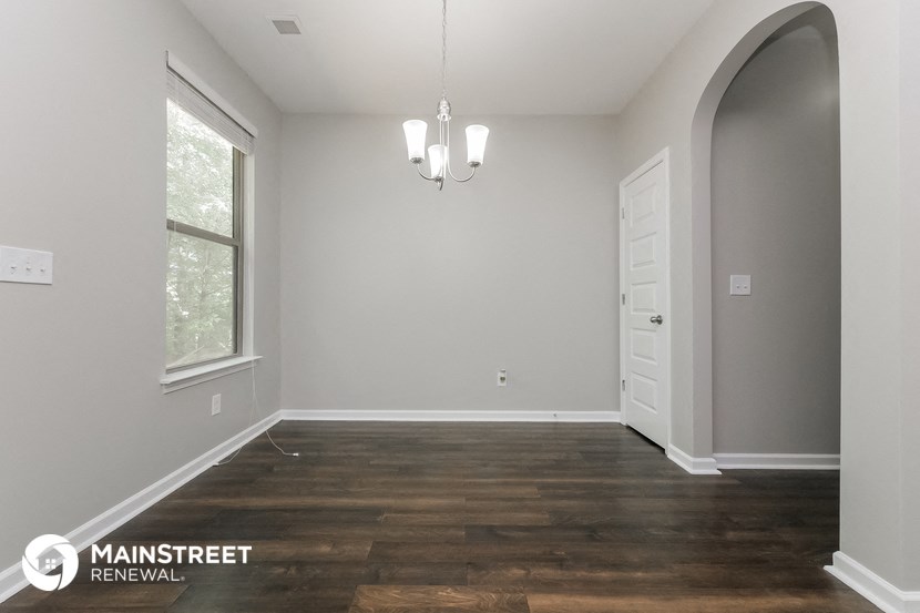 the living room of a new home with wood flooring and a white door
