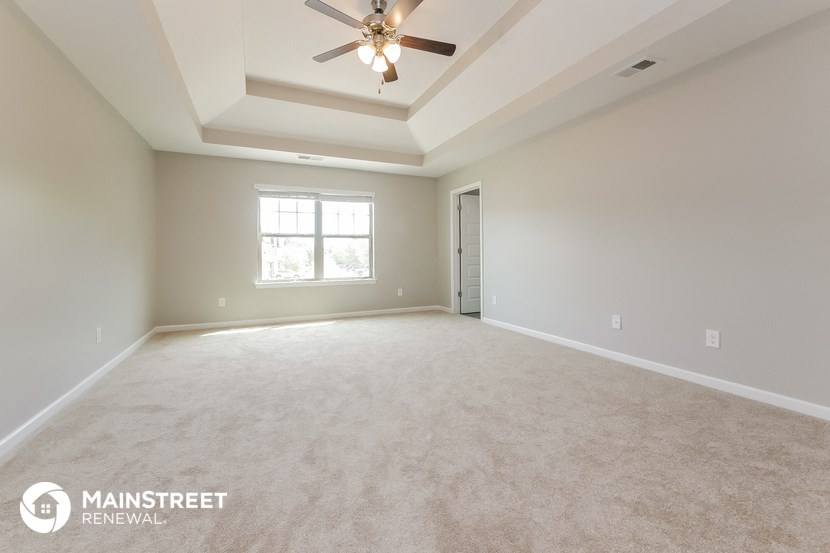 an empty living room with a ceiling fan and a window