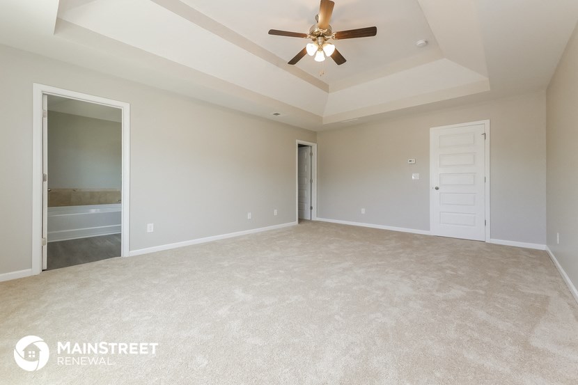 an empty living room with a ceiling fan and a closet