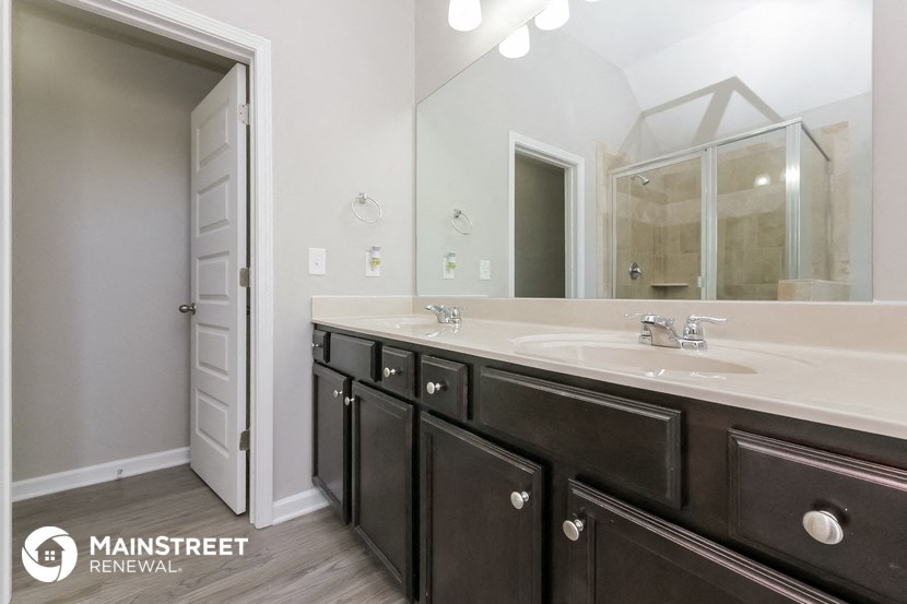 the master bathroom has a large mirror and dual sinks