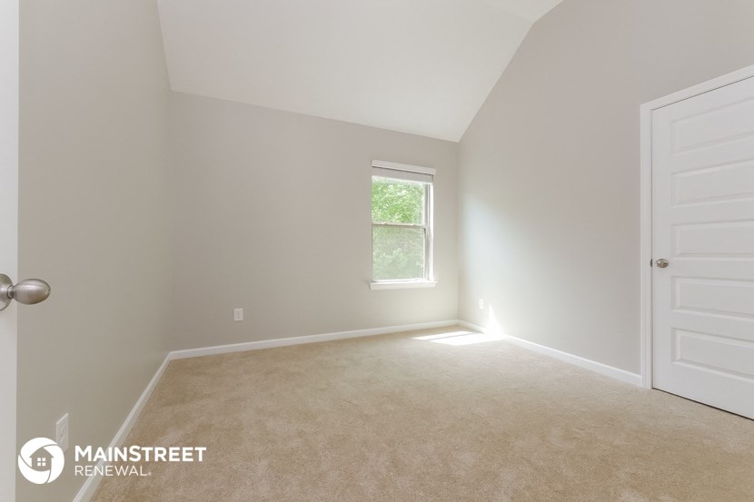 an empty room with a white door and a window