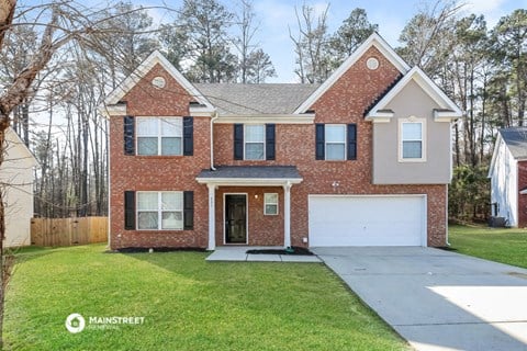 a brick house with a white garage door and a lawn