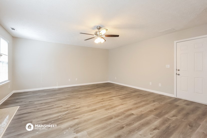 an empty living room with wood flooring and a ceiling fan
