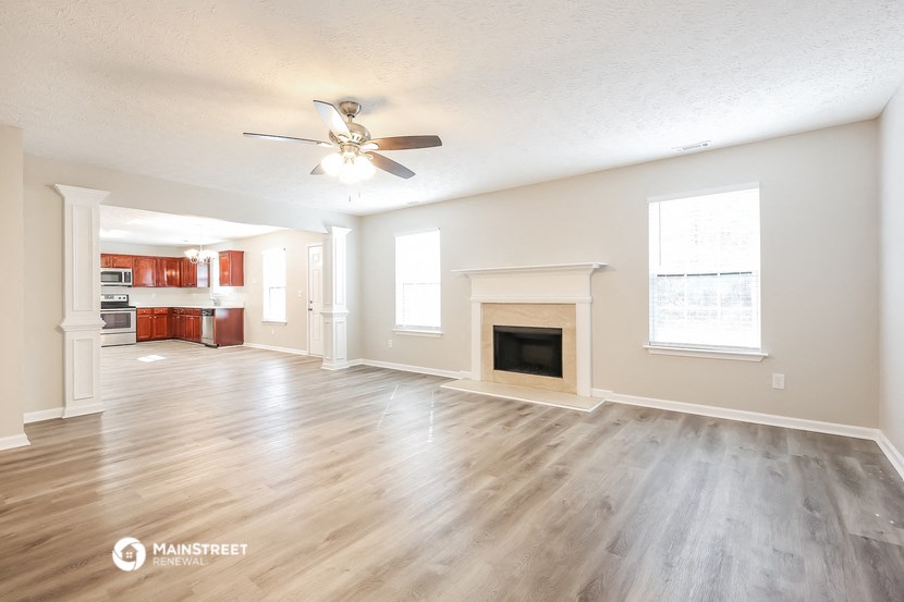 an empty living room with a fireplace and a ceiling fan