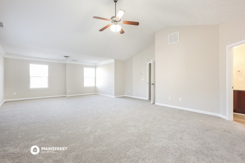 the living room of an empty house with a ceiling fan