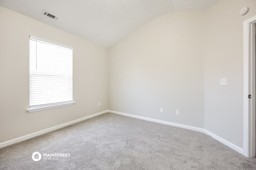 the living room of a home with carpet and a window