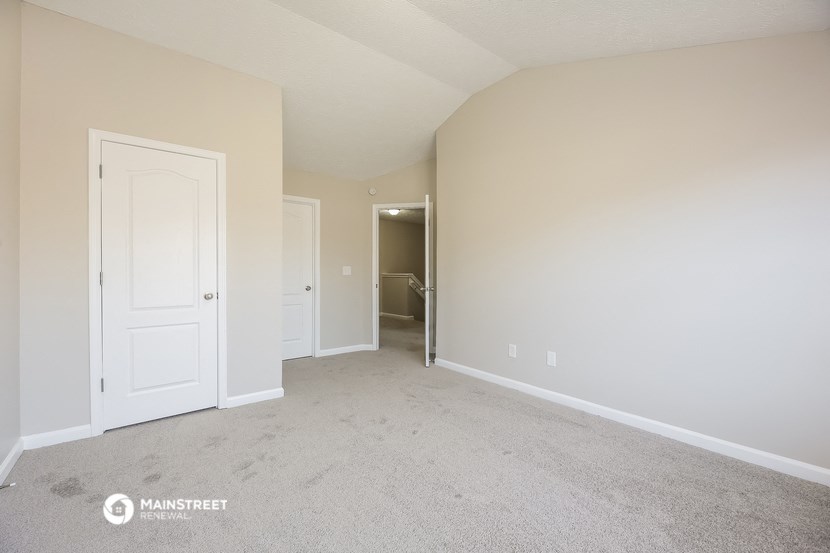 a spacious living room with carpet and a door to the bathroom