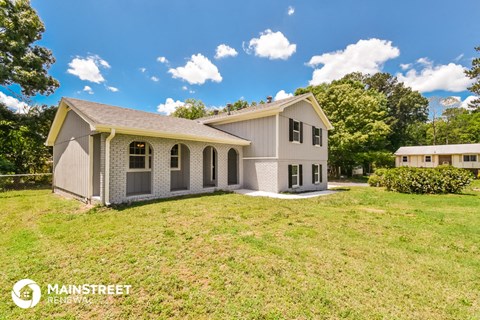 a home with a large yard and a gray house