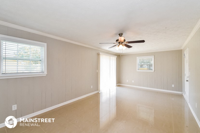 an empty living room with a ceiling fan and a window