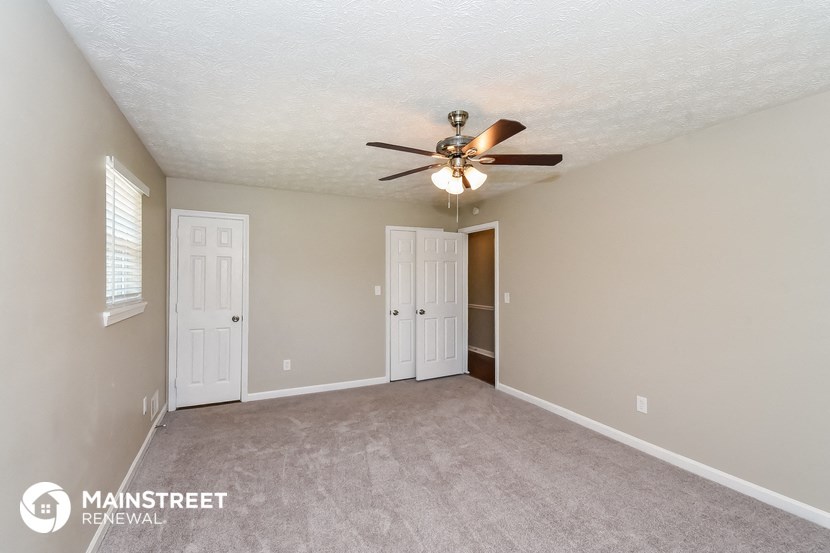 the spacious living room with ceiling fan and carpeting
