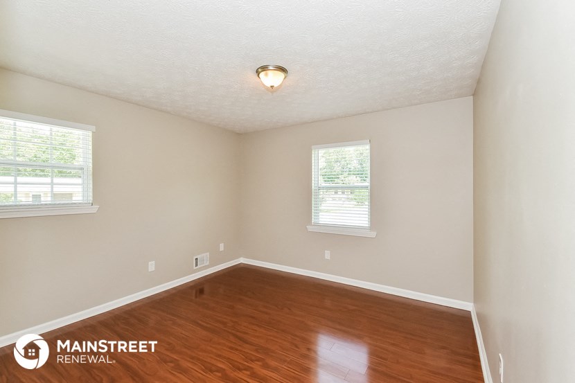 the spacious living room with hardwood flooring and two windows