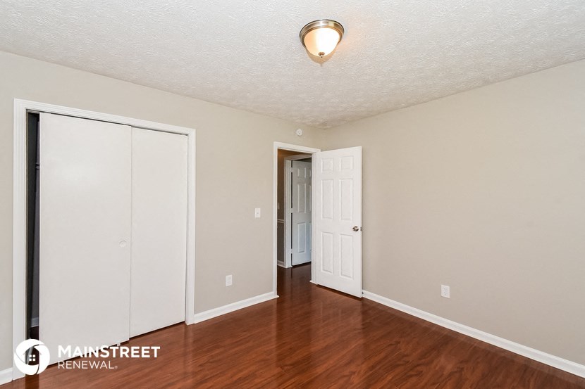 a living room with wood flooring and white walls and a door to a hallway