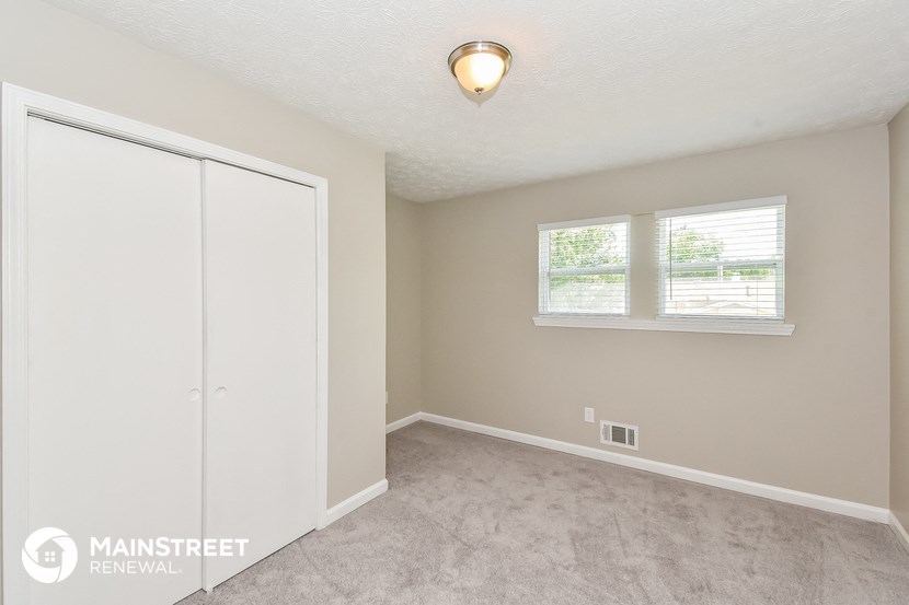 a bedroom with a carpeted floor and a closet and a window