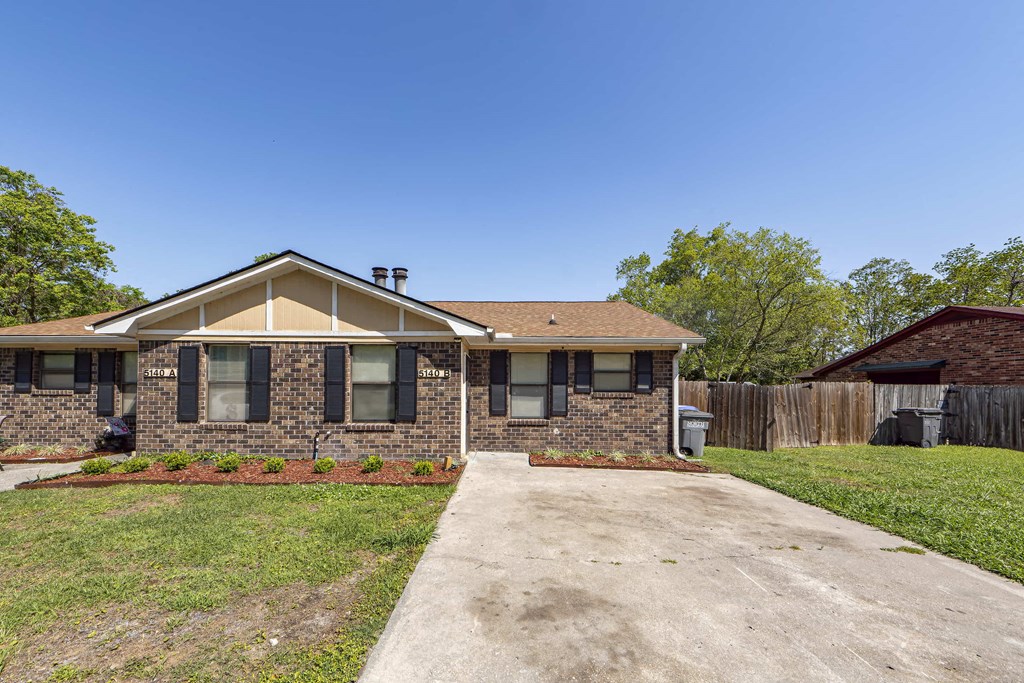 a small brick house with a driveway in front of it