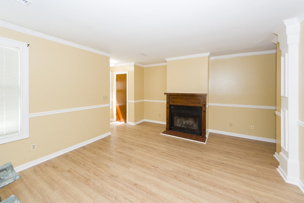 an empty living room with a fireplace and wooden floors