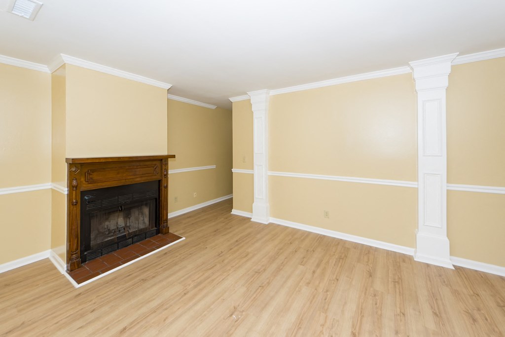 an empty living room with a fireplace and wooden floors