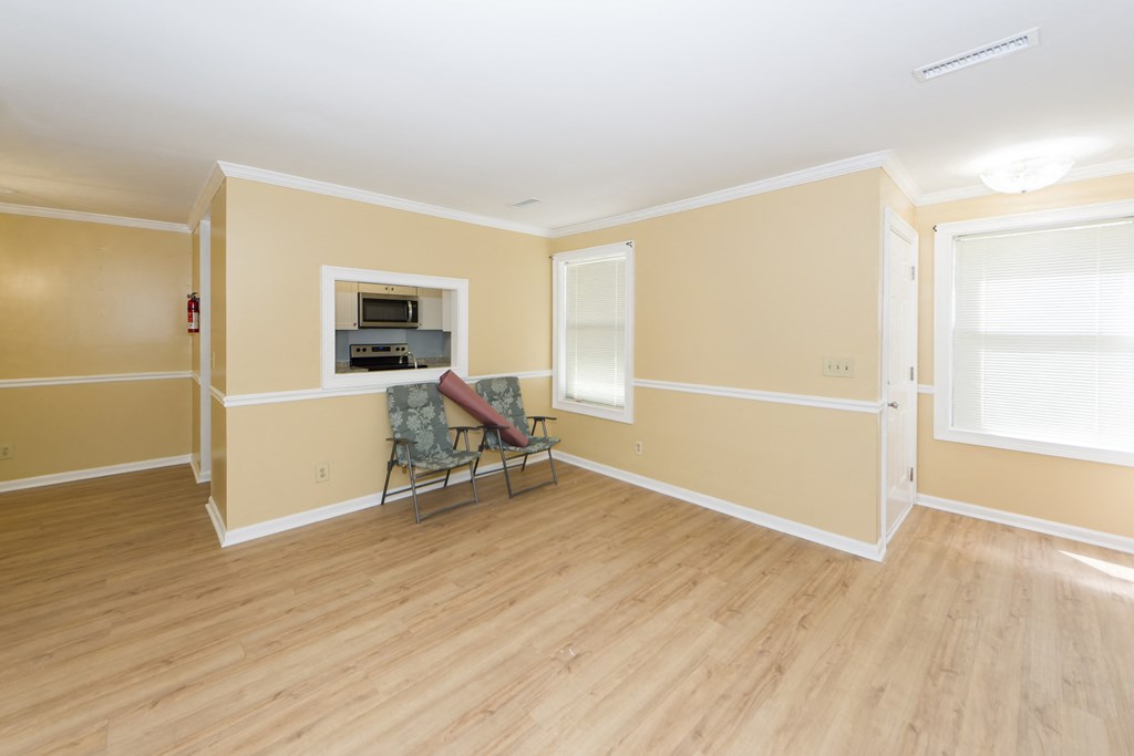 an empty living room with a hard wood floor and a couch and a window