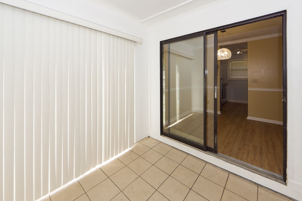 a sliding glass door in a living room with a tiled floor