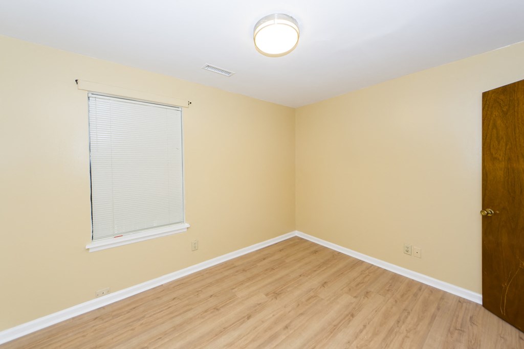 an empty room with a window and a wooden floor