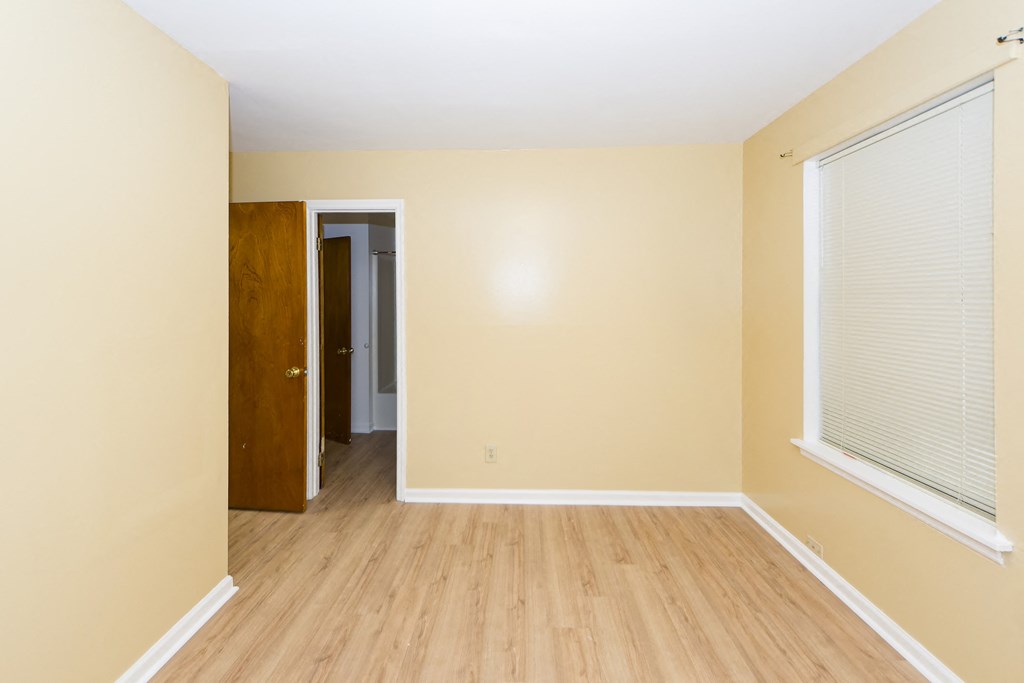 an empty room with wooden floors and a large window
