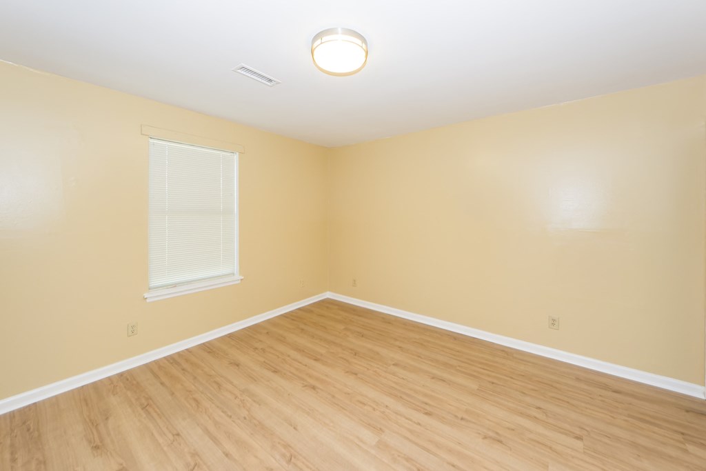 an empty room with wood floors and a window