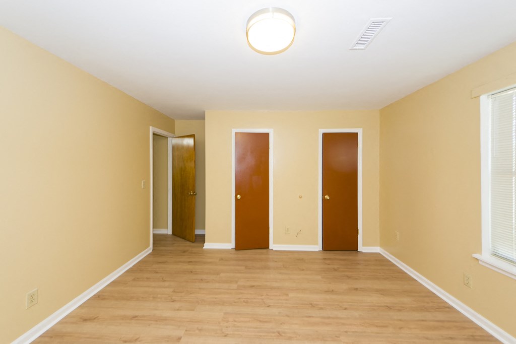 a empty room with a wooden floor and three doors