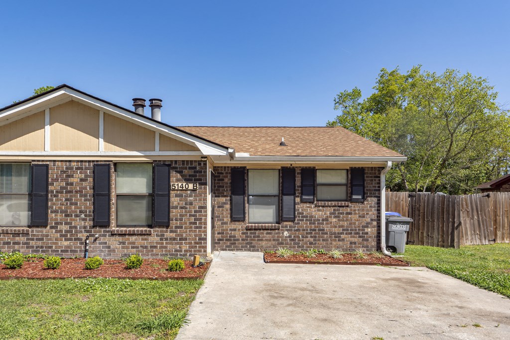 a small brick house with a yard and a driveway